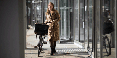 Dame met de fiets aan de hand naar het werk