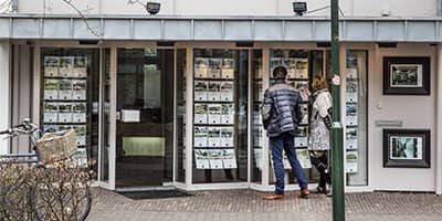 Man en vrouw voor de etalage van een makelaarswinkel