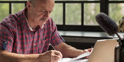 Oudere man met papieren en pen en laptop oudere-man-met-papier-en-pen400x200