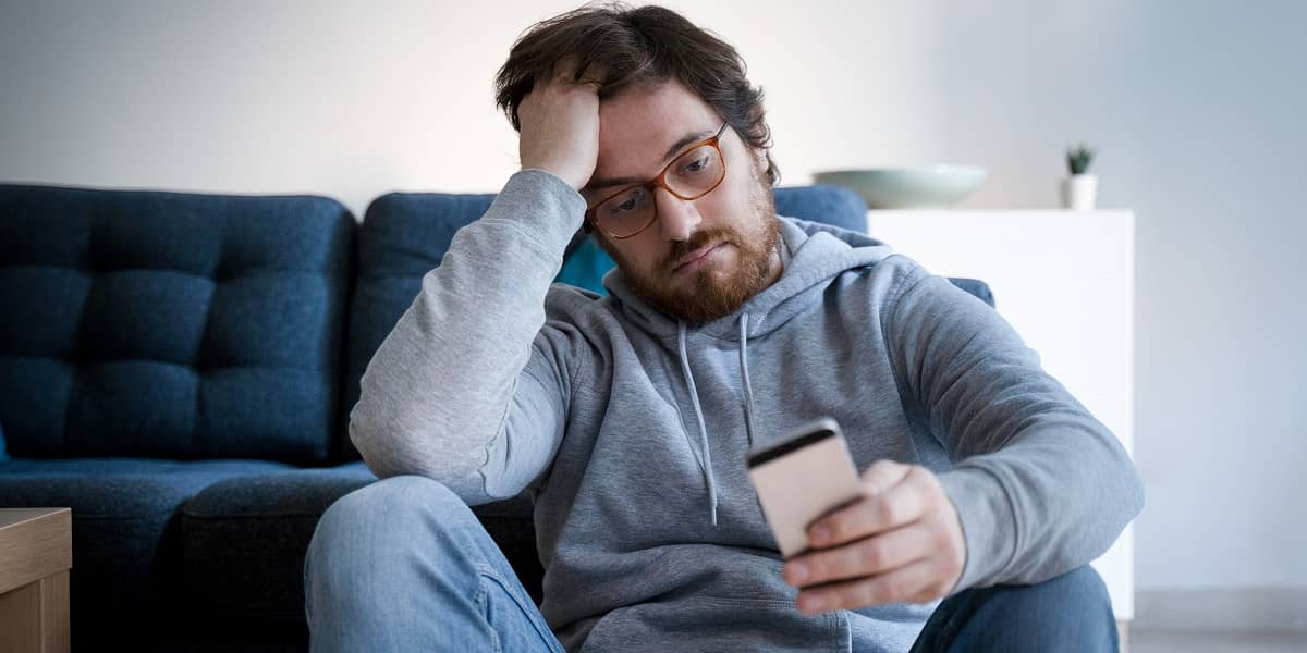 man kijkt vertwijfeld op telefoon